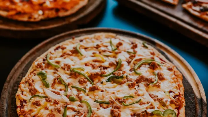 Pizzas recém-saídas do forno servidas em tábuas de madeira